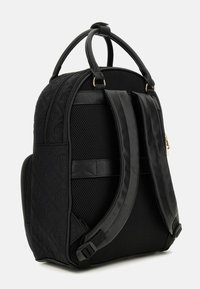 Sac à dos noir avec texture matelassée, panneaux en maille, sangles rembourrées ajustables, doubles poignées supérieures et détails de fermeture éclair dorée.