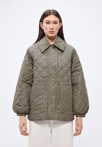 Prošívaná péřová bunda v hnědém a béžovém vzoru kosočtverců, s velkým límcem a objemnými rukávy s elastickými manžetami.