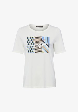 White short-sleeve T-shirt with geometric patterns in blue, beige, and black, and text reading "JUST BE Imagine" on the front.