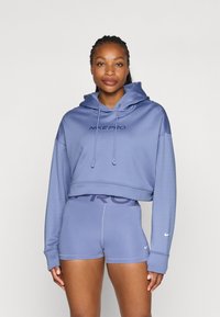 Hoodie e pantaloni corti Nike Pro in lavanda chiaro. La felpa ha un logo sulla parte anteriore e un cappuccio con coulisse; i pantaloni corti presentano una fascia in vita con logo ampio e cuciture sottili.