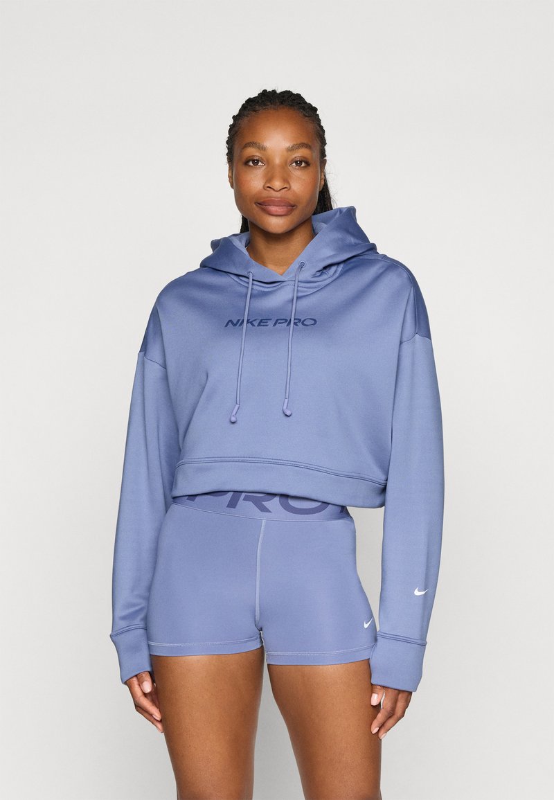 Hoodie e pantaloni corti Nike Pro in lavanda chiaro. La felpa ha un logo sulla parte anteriore e un cappuccio con coulisse; i pantaloni corti presentano una fascia in vita con logo ampio e cuciture sottili.