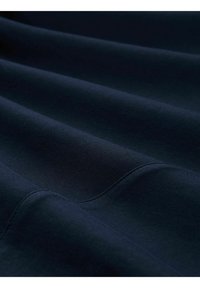 Tissu bleu marine avec une texture lisse, présentant de subtils plis doux et une finition uniforme. Couture droite le long des bords.