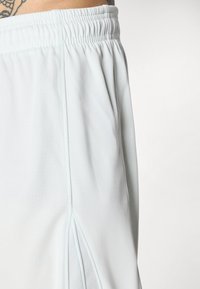 Světle modré sportovní šortky vyrobené z prodyšného materiálu, s elastickým pasem a bočními větracími detaily pro lepší pohyblivost.