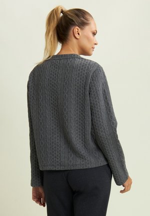 Cardigan grigio trapuntato con un motivo testurizzato, dotato di scollatura a girocollo e maniche lunghe. Il materiale sembra morbido e caldo, ideale per essere indossato a strati.