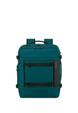 Türkisfarbener rechteckiger Rucksack mit mehreren Reißverschlussfächern, schwarzen Gurten und einem oberen Griff, für Reisen und den täglichen Gebrauch konzipiert.