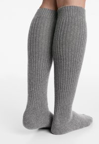 Knælange grå sokker lavet af blødt, ribbet materiale med en struktureret finish og forstærket tå og hæl. Enkel design, uden mønstre.