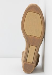 Semelle en toile marron d'espadrille avec un fond en caoutchouc texturé et antidérapant, comportant un branding en relief et un marquage de taille. Fabriqué en Espagne.