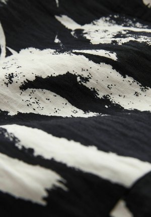 Black and white fabric featuring a bold, abstract pattern with brushstroke-like textures and a smooth, slightly shiny finish.
