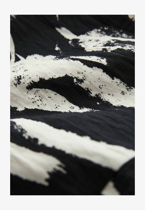 Black and white fabric featuring a bold, abstract pattern with brushstroke-like textures and a smooth, slightly shiny finish.