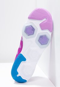 Sole sportovní obuvi s převážně bílým podkladem a purpurovými a modrými akcenty. Hexagonální polstrované prvky a texturovaný vzor pro lepší přilnavost.