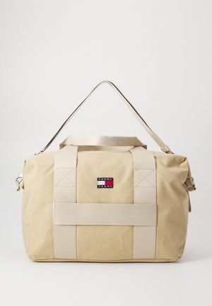 Beige szövet sporttáska krém színű pántokkal és cipzáras zárással. Kis logó folttal és geometrikus varrással a pántokon.
