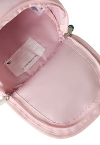 Light pink backpack interior with smooth fabric lining, zippered compartment, and a label for personal identification.