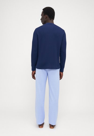 Jūras pukes garām piedurknēm ar teksturētu virsmu, kopā ar gaiši ziliem brīviem biksēm, abi izgatavoti no mīksta auduma. Nav redzamu rakstu vai akcentu.