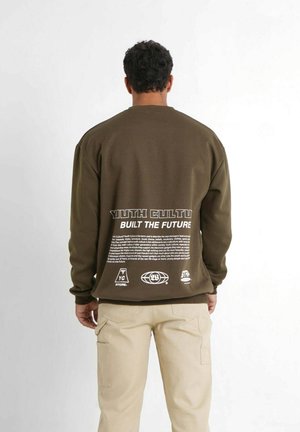 Sweatshirt de culoare verde măsliniu cu guler rotund, având text imprimat pe spate, prezentând un design grafic și diverse logo-uri. Materialul pare neted și casual.