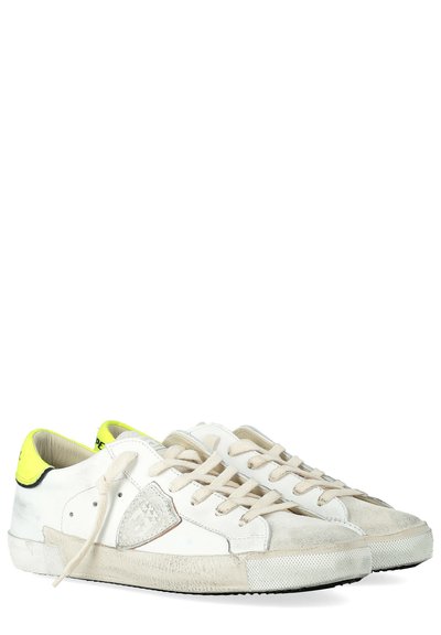 Sneakers bianche con accenti beige chiaro, caratterizzate da un pannello laterale testurizzato, lacci crema e un dettagli di tacco giallo brillante. Suola in gomma.