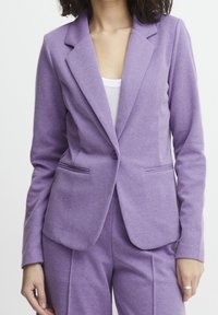 Lila skräddarsydd kavaj med slag, två framfickor och enknappsstängning. Tillverkad av textil med struktur, i kombination med matchande byxor.