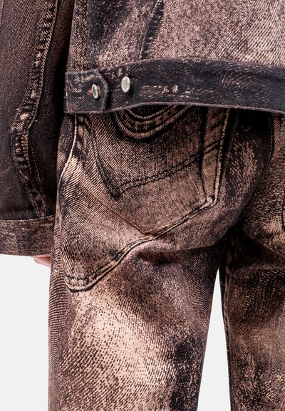 Giacca di jeans in tessuto invecchiato marrone e beige, con chiusure a bottone e dettagli di cucitura visibili, che evidenziano un motivo testurizzato.