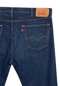 Jeans de mezclilla azul oscuro con corte recto, con costuras amarillas, bolsillos traseros y una etiqueta de cuero marrón que muestra los detalles de la marca.