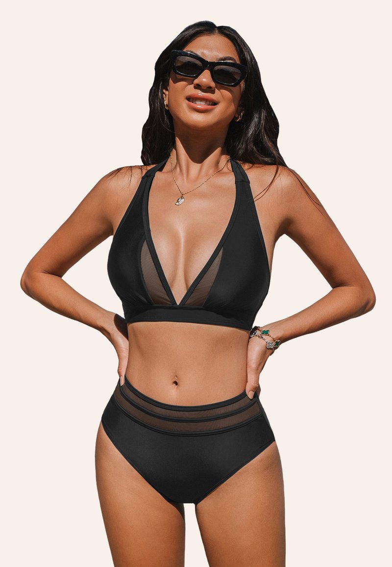 Set di bikini nero con top halter profondo caratterizzato da pannelli in rete trasparente e slip a vita alta con due strisce in rete lungo l'elastico.
