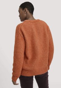 Texturiertes, übergroßes Sweatshirt in einem Sonnenuntergangsorange, mit runder Halslinie und geripptem Saum. Strickdesign mit einem gemütlichen Aussehen.