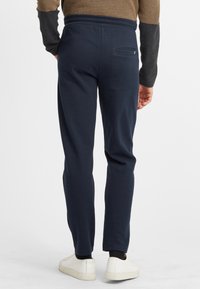 Marinblå joggers gjorda av mjuk bomullsblandning, med dragsko i midjan, tapered ben och en bakficka.