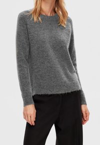 Harmaa, pörröinen neulepaita, jossa on pyöreä kaula-aukko ja pitkät hihat. Helma on takaa hieman pidempi, tarjoten rentoa istuvuutta.