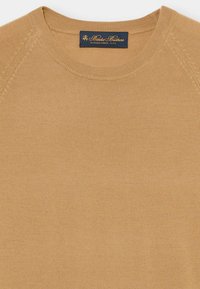 Tan crewnecktrui met geribde kraag en gestikte schouderdetails, met Brooks Brothers-label in de halslijn.
