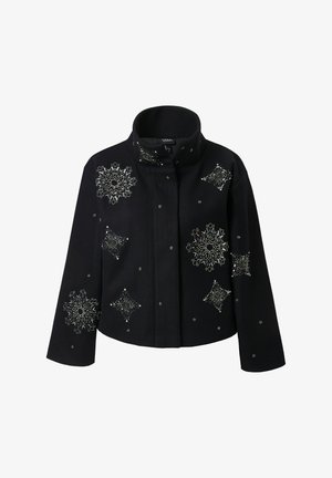 Veste noire cropped avec un col montant, ornée de motifs en perles argentées en forme d'étoiles et de flocons de neige sur le devant et les manches.