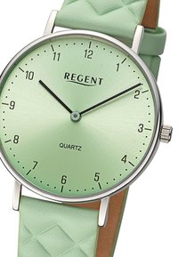 Montre en quartz verte avec un cadran à finition mate, des accents en argent et un bracelet en silicone texturé vert menthe. Présente des index horaires minimalistes.