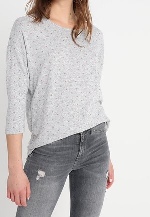 Gray long-sleeve top with a round neckline and small floral patterns, paired with light gray distressed skinny jeans.