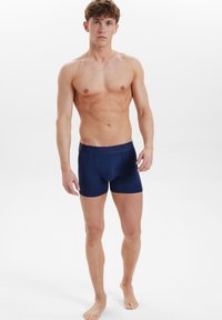 Navyblå herrboxershorts med mjuk tyg, elastisk midja och figursydd design, som visar en slät textur och sömlös konstruktion.