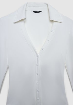 White long-sleeve shirt featuring a V-neckline, button front closure, and a smooth fabric texture. Label reads "CALLIOPE."