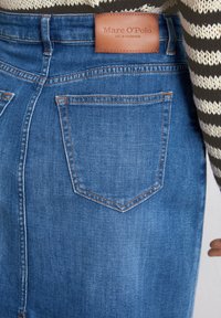 Jeansrok in medium blauw met oranje stiksel, voorzien van een leren merklabel op de tailleband en twee achterzakken.