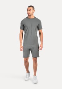 Grijs sport T-shirt met korte mouwen, gecombineerd met bijpassende grijze shorts. Gedragen met witte sneakers, met een gladde textuur en een aansluitend ontwerp.