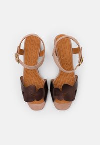 Braune Ledersandalen mit einem blütenförmigen Riemen, beigem Knöchelriemen und strukturiertem Korkfußbett. Schnallenbeschlag am Riemen.