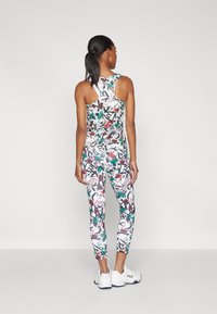 Bunt gemustertes Sportset bestehend aus einem ärmellosen Top und figurbetonten Leggings mit floralem Muster, hergestellt aus atmungsaktivem Material.