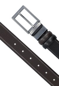 Brązowy paski o teksturowanej powierzchni z metalową klamrą w kolorze srebrnym. Klamra ma kształt prostokątny, grawerowane logo marki oraz pięć otworów do regulacji na pasku.