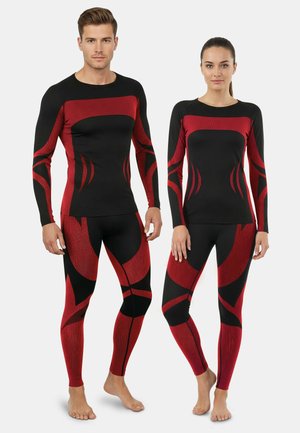 Schwarze Sportoberteile und Leggings mit roten abstrakten Mustern. Der Stoff wirkt strukturiert, hat lange Ärmel und ein figurnahes Design.