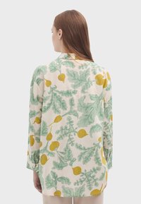 Camicia leggera e traspirante color crema con stampa di ravanelli verdi e gialli. Presenta maniche lunghe e colletto.