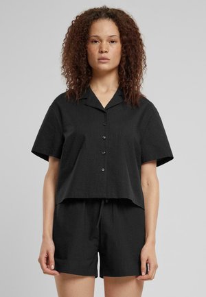 Black short-sleeved shirt with a collar and button front, paired with matching black shorts. Both feature a textured fabric finish.
