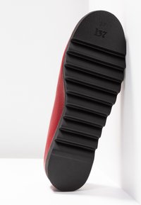 Semelle de chaussure rouge avec des rainures horizontales profondes et le numéro de taille 37 embossé près de la zone des orteils, présenté sur fond blanc.