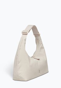 Sac à épaule beige avec une forme arrondie, fabriqué en tissu lisse. Dispose d'une large sangle et d'une fermeture éclair, marqué d'un logo du fabricant.