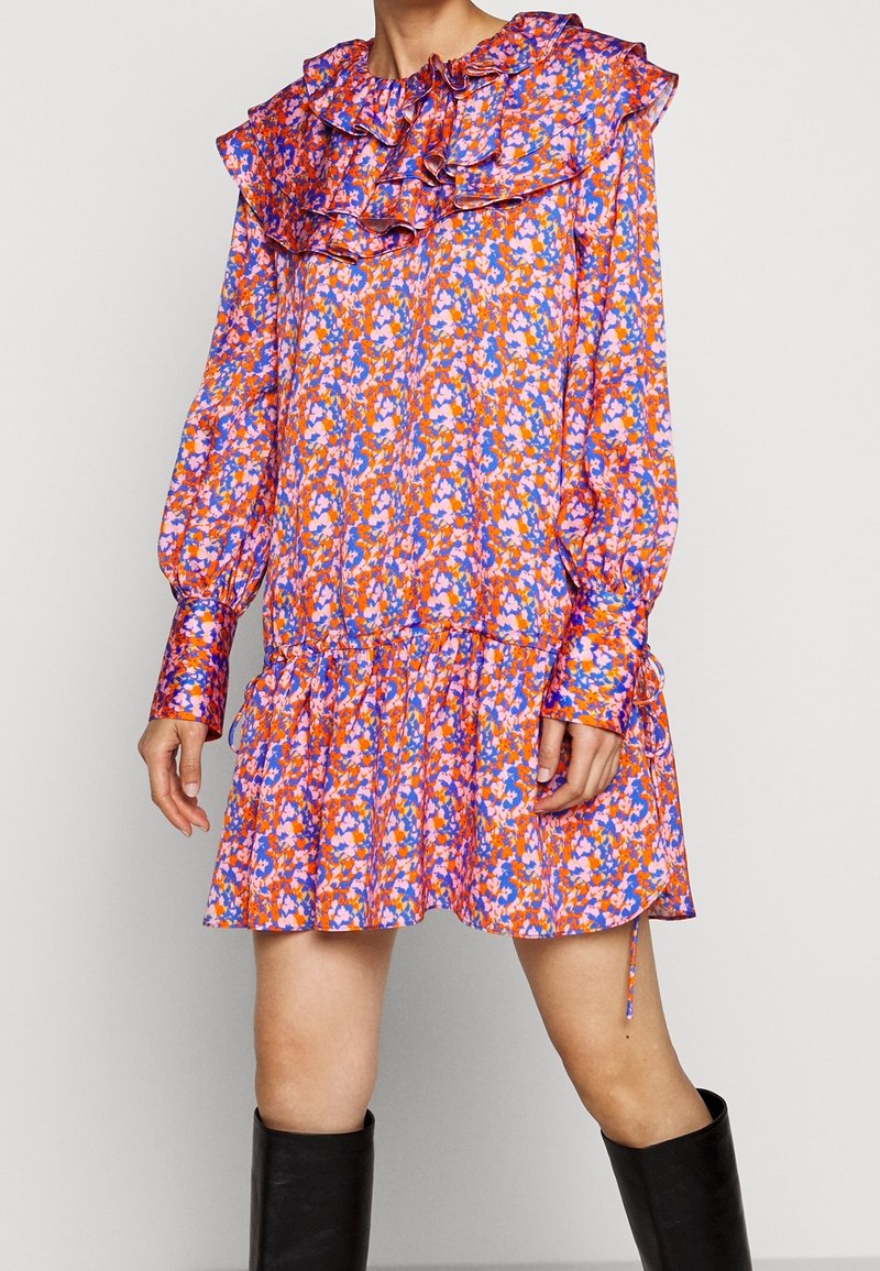 Robe fleurie avec un col volanté, des manches longues et une jupe à niveaux. Présente un motif coloré de teintes roses, oranges et bleues. Tissu doux.