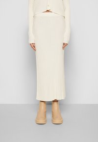 Ribbade, krämfärgade stickade kjol som sträcker sig till anklarna, i kombination med kraftiga, beige ankelstövlar.