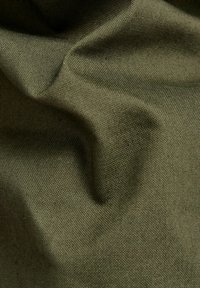 Texturovaná olivově zelená látka s jemnými záhyby. Materiál vypadá odolně, má tkaný povrch a jemný lesk.