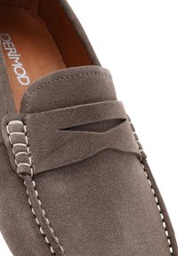Zapato mocasín de ante marrón con un acento cosido y un cuello suave. Presenta un panel superior decorativo y un forro interior suave.