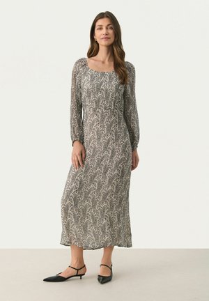 Robe à manches longues de longueur intermédiaire avec un décolleté carré, présentant un motif ondulant noir et blanc sur un tissu léger.
