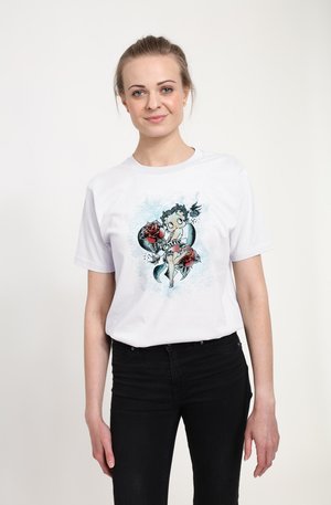 T-shirt en coton blanc avec une illustration graphique colorée d'une femme entourée de roses et de rubans. Manches courtes et coupe classique.