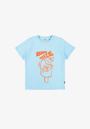 Gaiši zilā kokvilnas T-kreklā ar oranžu grafiku popsikla ar izteiksmīgu seju un tekstu "BRAIN FREEZE". Īsas piedurknes.