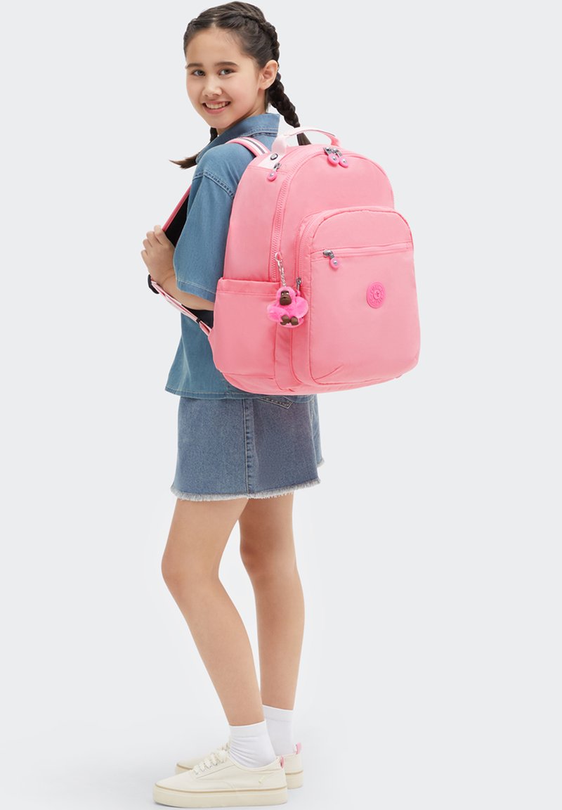 Rosa ryggsäck med texturerad finish, två framfickor med dragkedja och ett hänge. Justerbara remmar och en logopatch på framsidan.